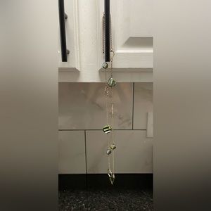 Women’s long gold necklace with green stones and geometric patterns